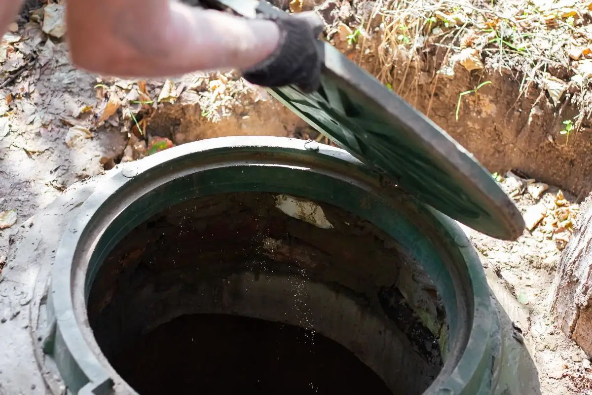 close up of man opening sewer hatch to a septic tank