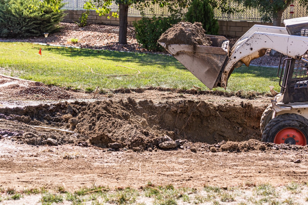 Small bulldozer digging in a backyard for a pool installation