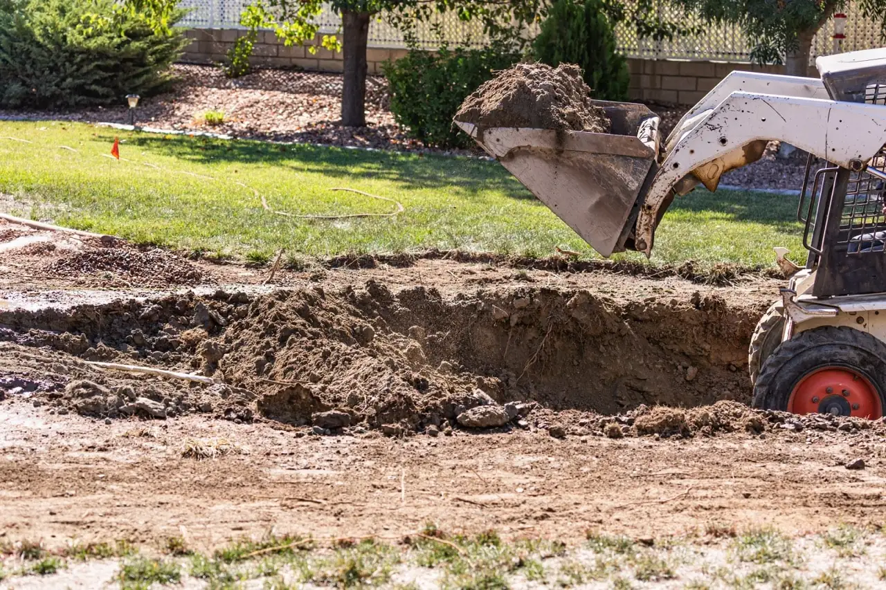Small bulldozer digging in a backyard for a pool installation